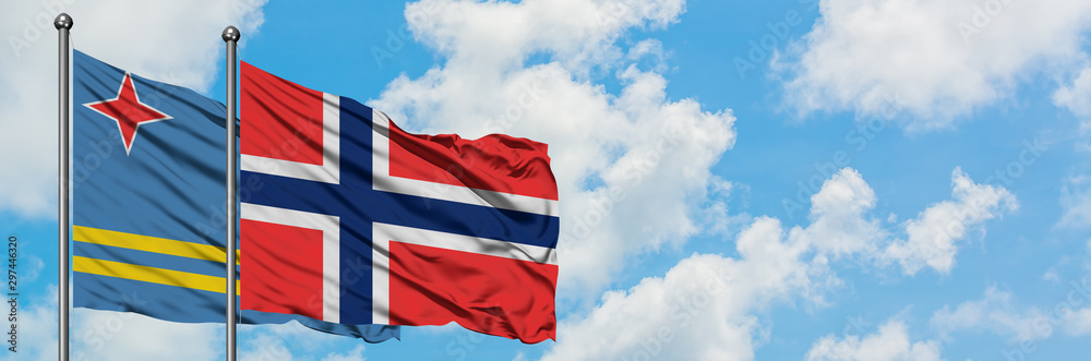 Fototapeta premium Aruba and Bouvet Islands flag waving in the wind against white cloudy blue sky together. Diplomacy concept, international relations.
