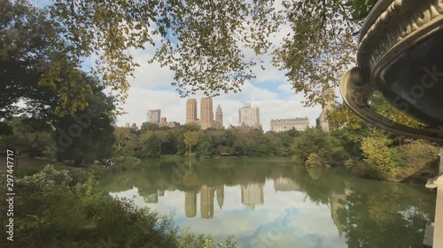 A dollying establishing shot of the skyline of Manhattan as seen from the Bow Bridge in Central Park on an overcast Autumn day. The Lake in the foreground with upscale apartment buildings in the dista photo