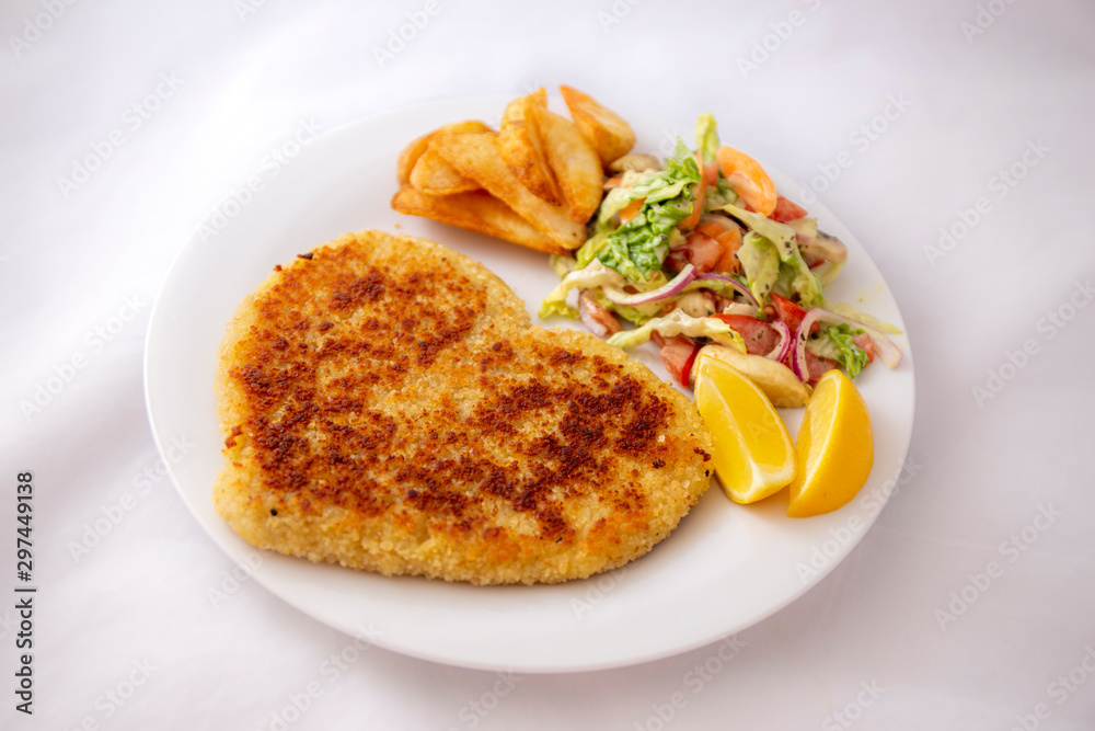 Heart shape Chicken Schnitzel with salad, fried potato wedges Heart shape Chicken Schnitzel with salad, fried potato wedges
