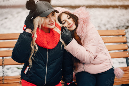Fashionable girls in a winter city. Stylish ladies in a cute jackets. Women sitting on a bench