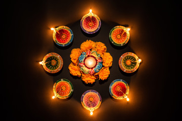 Happy Diwali - Clay Diya lamps lit during Dipavali, Hindu festival of lights celebration. Colorful traditional oil lamp diya on black background
