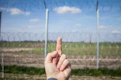 Middle finger on a hand of a protestor pointing at Border fence between Rastina (Serbia) & Bacsszentgyorgy (Hungary). This border wall was built in 2015 to stop the incoming refugees & migrants photo