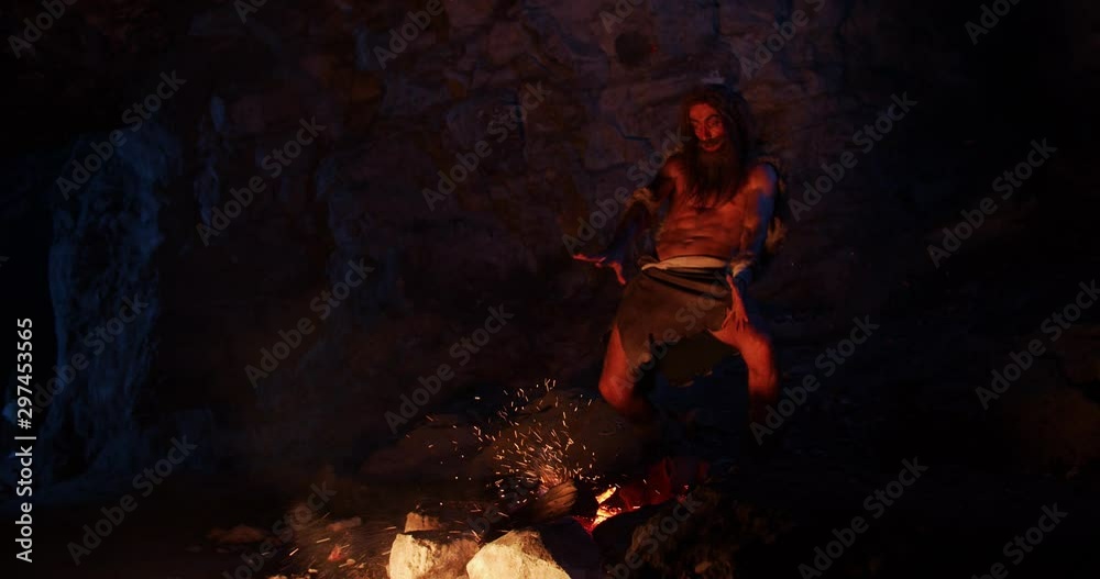 Man play with fire neanderthals wearing animal skin stand sorcery waving hands over fire at night in a cave stone fun male history evolution nature homo sapiens primitive campfire slow motion Man play with fire neanderthals wearing animal skin stand sorcery waving hands over fire at night in a cave stone fun male history evolution nature homo sapiens primitive campfire slow motion