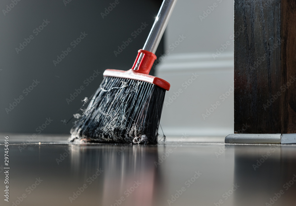 Dirty broom handle resting on a wall with sunlight.