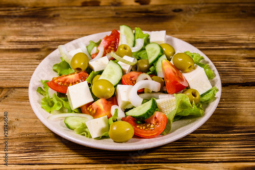 Ceramic plate with greek salad on wooden table