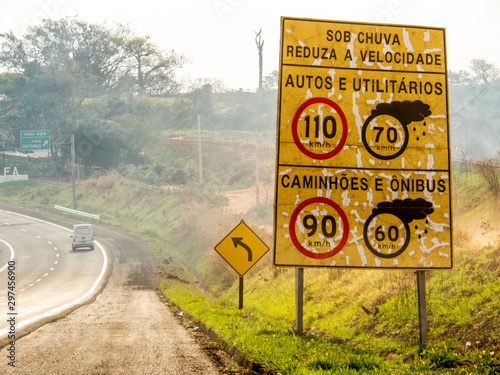 Signpost indicating speed limit on dry and wet roads on Comandante João Ribeiro de Barros Highway, SP 294, near the entrance of Jafa district, in Garca municipality