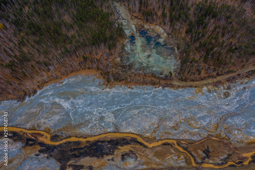 Aerial view drone flying forward over polluted river with destroyed ecosystem and copper tailing dump poisoning ground and water air emissions from industry environmental disaster in South Ural