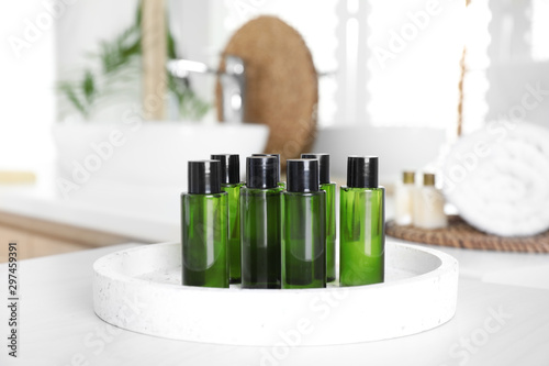 Mini bottles with cosmetic products on white table in bathroom