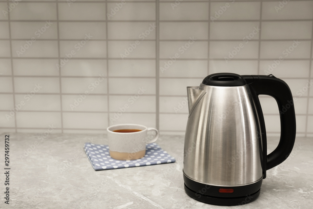 Modern electric kettle and cup of tea on grey marble kitchen counter. Space for text Modern electric kettle and cup of tea on grey marble kitchen counter. Space for text