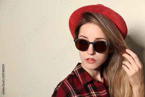 Young woman wearing stylish sunglasses on beige background. Space for text © New Africa