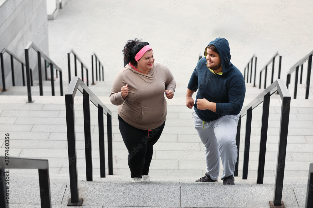 Overweight couple running up stairs together outdoors - obrazy, fototapety, plakaty 