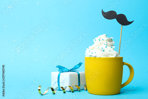 Canvas Print Cup of creamy drink with mustache and gift box on blue background, space for text