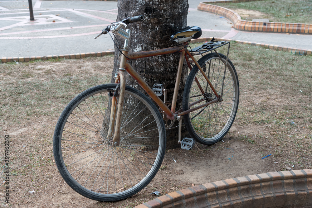 Old bicycle next to a tree in a park of a country town. Colombia. Old bicycle next to a tree in a park of a country town. Colombia.