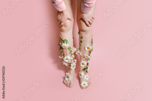 Legs in flowers camomiles on a pastel background. The concept of pain, swelling of the legs, varicose veins of pregnant women, laser hair removal	