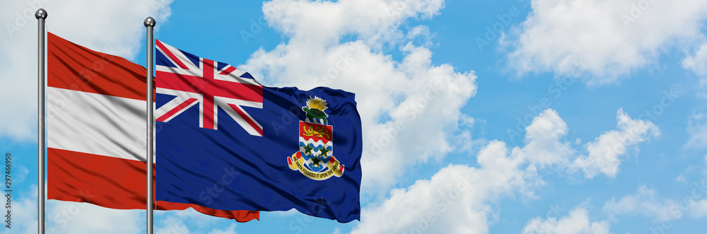 Fototapeta premium Austria and Cayman Islands flag waving in the wind against white cloudy blue sky together. Diplomacy concept, international relations.