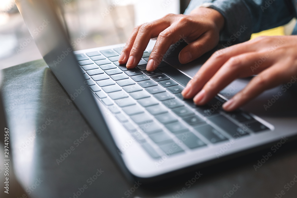 Closeup image of a woman working and typing on laptop computer keyboard