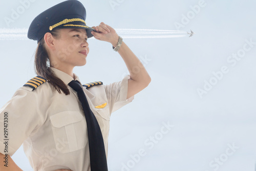 Canvastavla A female captain pilot standing next to an airplane at the airport