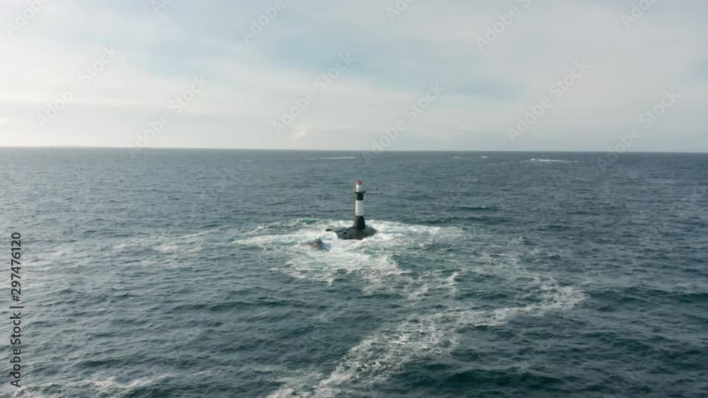 Lighthouse standing alone in the middle of the sea with waves crashing against it Lighthouse standing alone in the middle of the sea with waves crashing against it