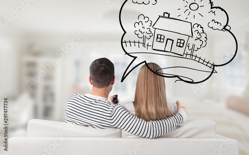 Young Thoughtful Couple Sitting On Sofa Thinking Of Getting Their Own House