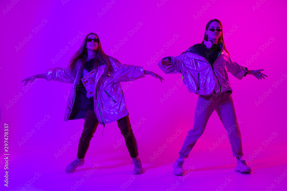 Young stylish girls dancing in the Studio on a colored neon background. Music dj poster design. Young stylish girls dancing in the Studio on a colored neon background. Music dj poster design.