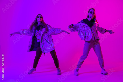 Young stylish girls dancing in the Studio on a colored neon background. Music dj poster design.