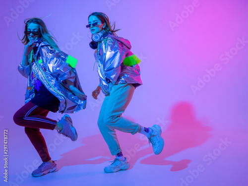 Fotografie Young stylish girls dancing in the Studio on a colored neon background