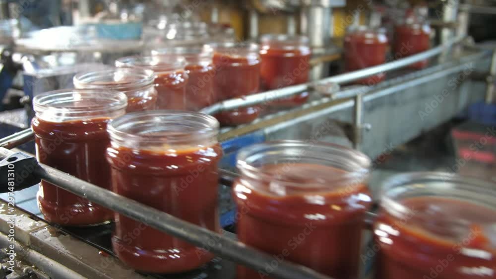 Fuming tomato paste banks moving on a metallic line without lids in tomato plant