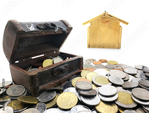 Many coins and mini Treasure Chest. Concept Save money for home lone on white background. Many type of coins and blur wooden little home for background. Isolated on white background with clipping paht photo