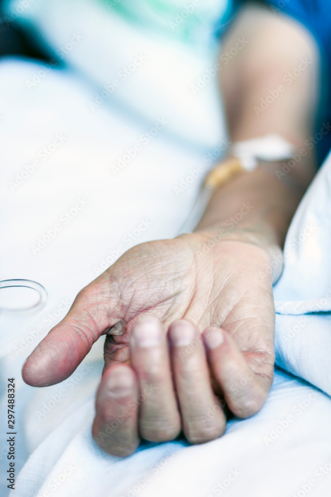 Hand of patient in serious condition is given a medicine through a dropper (healthcare background with an intravenous system).