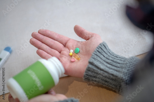 Man wearing grey sweater having pills on palm