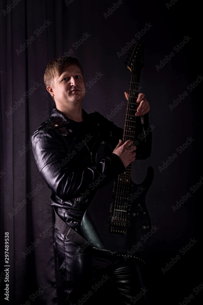 Handsome guitarist playing his electric guitar on black background