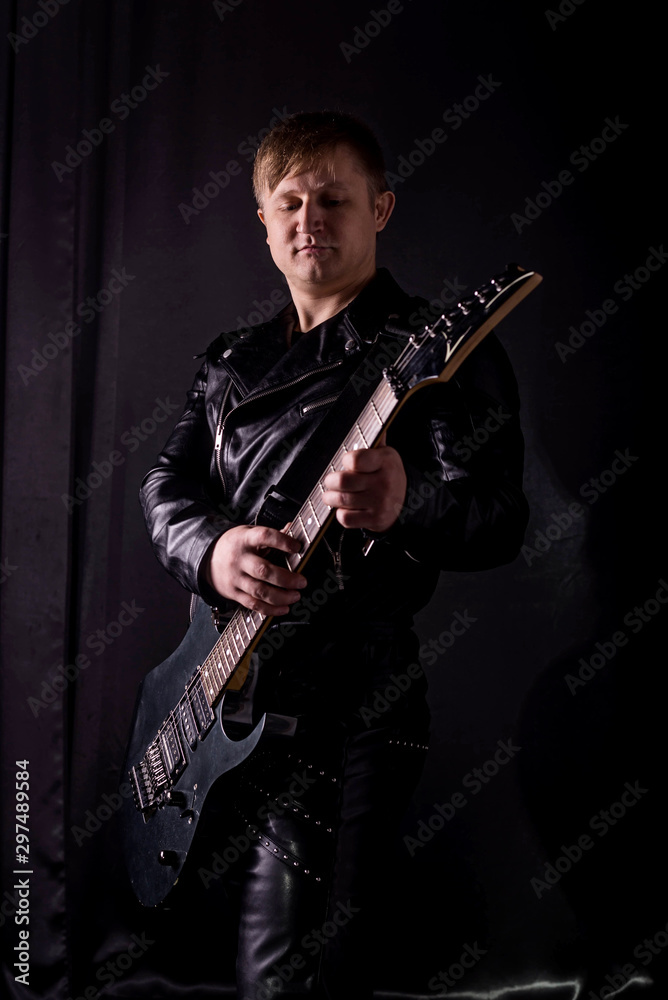 Fototapeta premium Handsome guitarist playing his electric guitar on black background