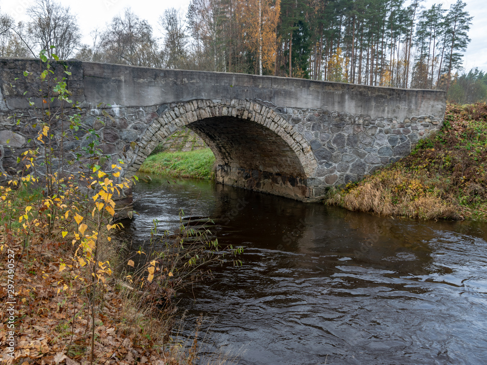 beautiful stone arched bridge over the small river, autumn day