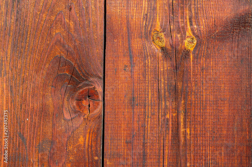 Old wooden boards with peeling red paint. Background of wood texture with peeling paint on a sunny day.