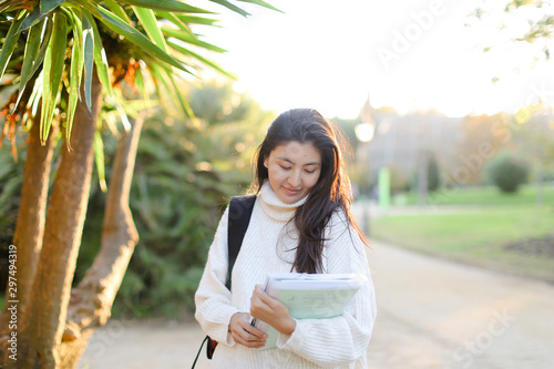 hinese girl with documents walking in park. photo