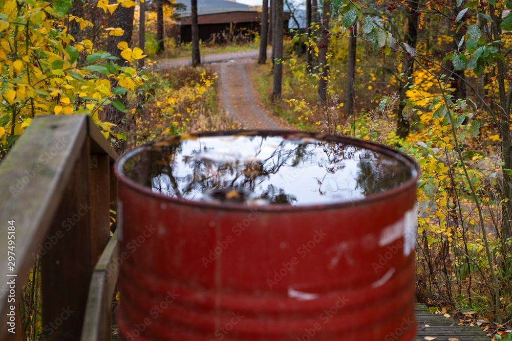 Autumn park and a barrel of water. Yellow leaves float in the water