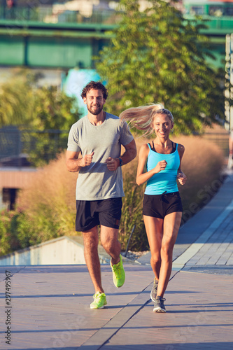 Modern woman and man jogging / exercising in urban surroundings near the river. © astrosystem