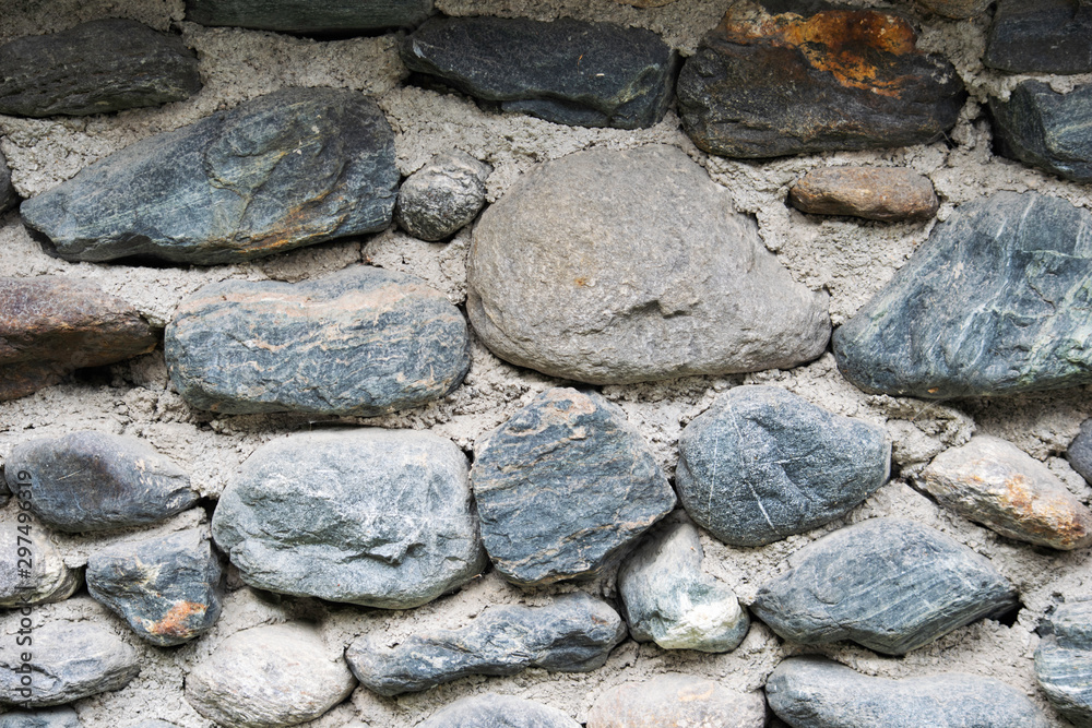 Fototapeta premium a fragment of stone wall lined with cobblestones background texture