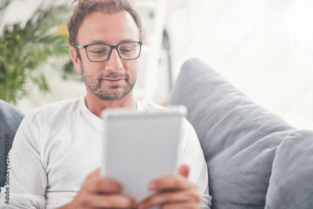 Man using tablet and sufring on the internet in his living room. Man using tablet and sufring on the internet in his living room.