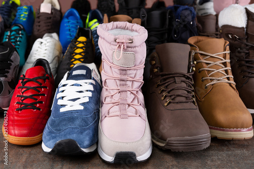 many varied shoes stand in a row on a wooden board, concept, assortment boots