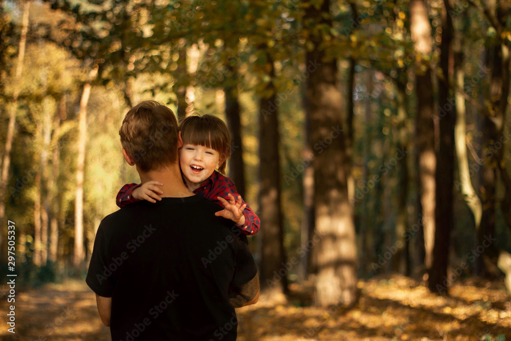 Father and his toddler son walking during the hiking activities in autumn forest at sunset Father and his toddler son walking during the hiking activities in autumn forest at sunset