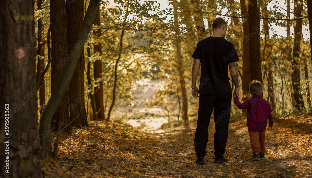 father with son in the autumn forest looks into the distance