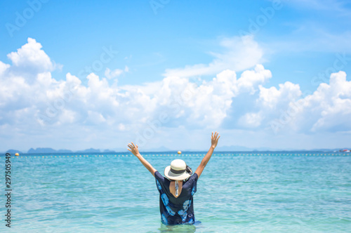The image behind the woman raise their arms and a hat In the sea background sky and cloud.