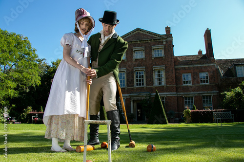 Obraz na płótnie Handsome man and beautiful woman dressed in vintage clothing on lawn in front of