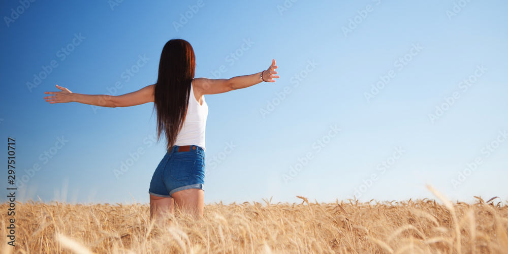 Happy woman enjoying the life in the field. Nature beauty, blue sky,white clouds and field with golden wheat. Outdoor lifestyle. Freedom concept. Woman jump in summer field - obrazy, fototapety, plakaty 