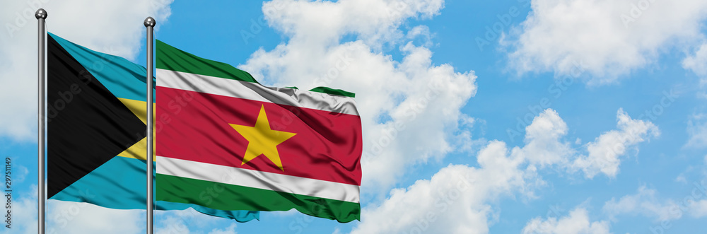Bahamas and Suriname flag waving in the wind against white cloudy blue sky together. Diplomacy concept, international relations. Bahamas and Suriname flag waving in the wind against white cloudy blue sky together. Diplomacy concept, international relations.