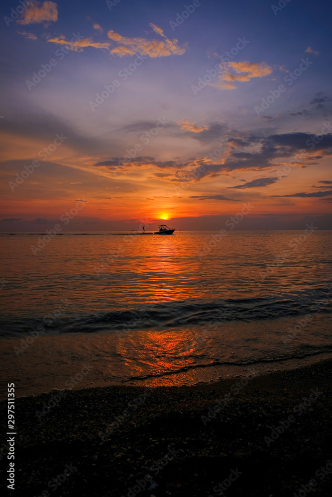 Beautiful sunset and blue sky, Silhouette surfing with a towing boat on the sea at Pattaya Beach