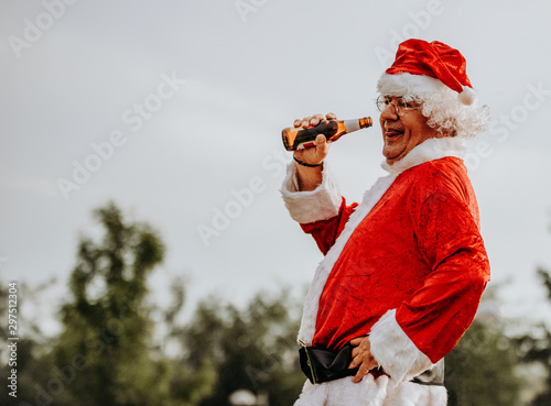 Stock photo of Profile of santa claus without beard drinking a beer. Christmas time
