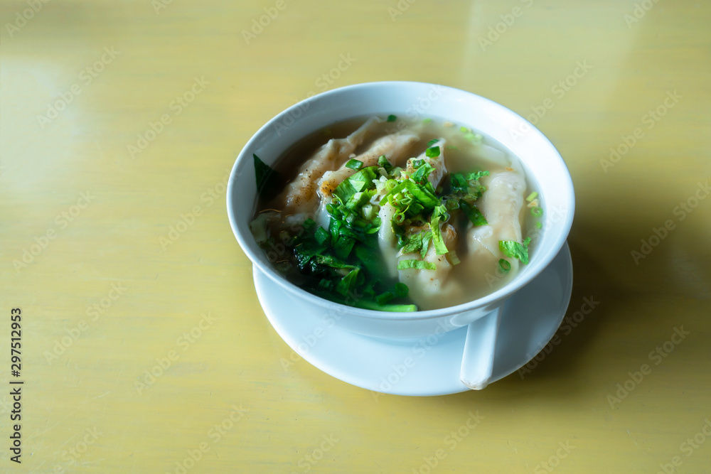 Shrimp wonton with braised pork in soup on wooden table / Select focus image Shrimp wonton with braised pork in soup on wooden table / Select focus image