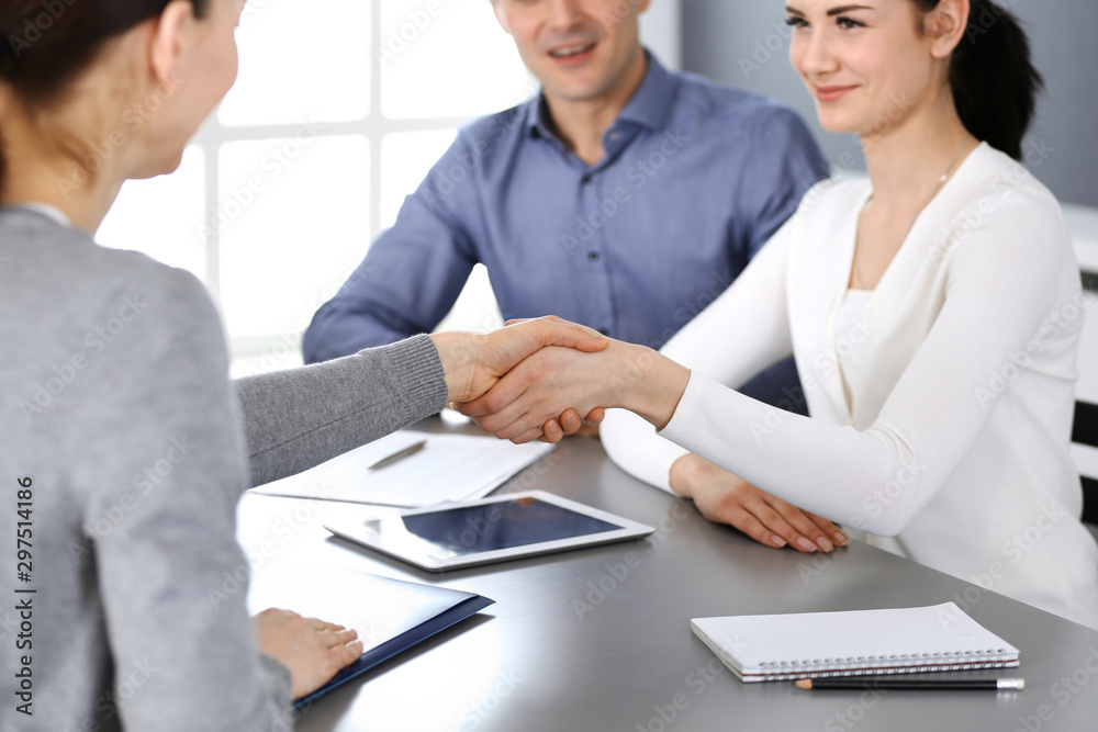 Fototapeta premium Group of business people shaking hands after discussing questions at meeting in modern office. Handshake close-up. Teamwork, partnership and agreement in business concept